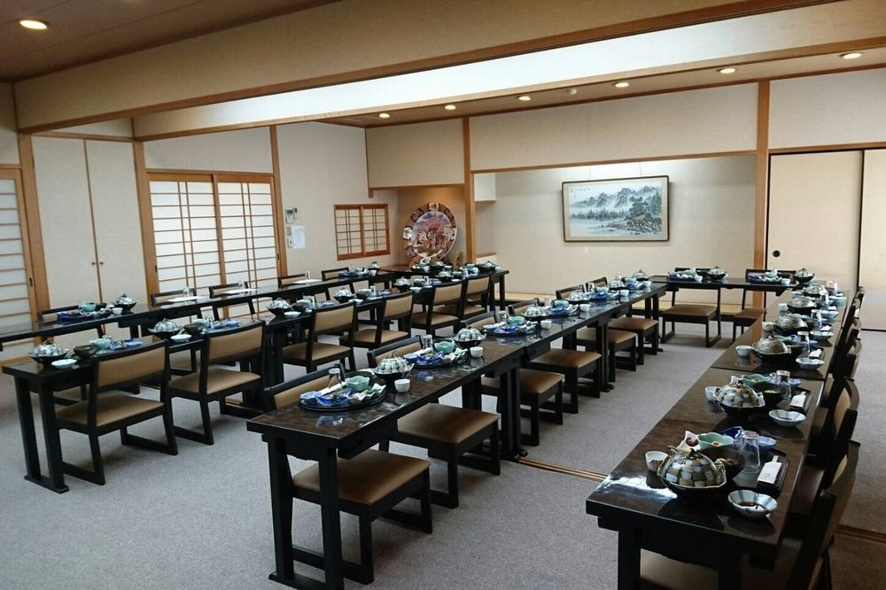テーブル席に並ぶ器と配膳前の準備が見える店内の別角度写真